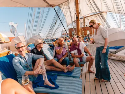 Passagiere sitzen mit Getränken in Liegestühlen auf dem sonnigen Teakdeck der Sea Cloud Spirit.