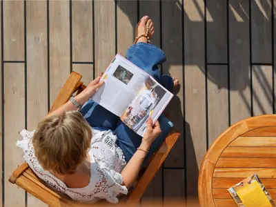 Blick von oben auf eine Frau, die entspannt ein Magazin im Liegestuhl auf dem Teakdeck der Sea Cloud Spirit liest.
