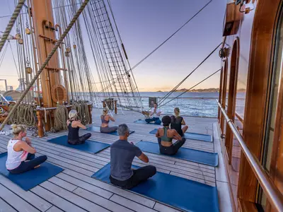 Eine Gruppe von Passagieren praktiziert Yoga auf Matten auf dem Holzdeck an Bord der Sea Cloud Spirit.