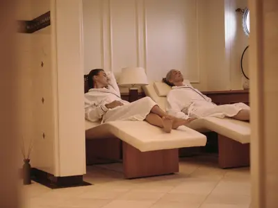 Zwei Frauen in weißen Bademänteln entspannen auf Liegen im Spa-Bereich an Bord der Sea Cloud Spirit.