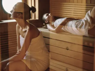 Zwei Frauen entspannen in der warm beleuchteten Sauna im Spa-Bereich an Bord der Sea Cloud Spirit.