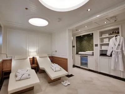 Blick in den luxuriösen Spa-Ruheraum an Bord der Sea Cloud Spirit mit weißen Entspannungsliegen und Bademänteln.