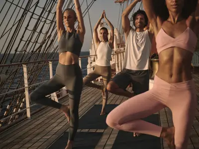 Vier Passagiere praktizieren die Baum-Pose beim Yoga auf dem Holzdeck an Bord der Sea Cloud Spirit.