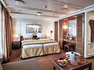 Luxuriöse Suite an Bord der Sea Cloud Spirit mit Doppelbett, Gemälde, Holzschränken, Frisiertisch und Sektkühler.