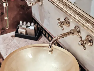 Nahaufnahme eines Waschtischs mit goldenen Armaturen und Glaskörper im Bad einer Suite an Bord der Sea Cloud Spirit.
