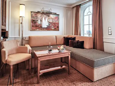 Wohnbereich einer Veranda-Suite an Bord der Sea Cloud Spirit mit gemütlichem Sofa, Holztisch und Bild.
