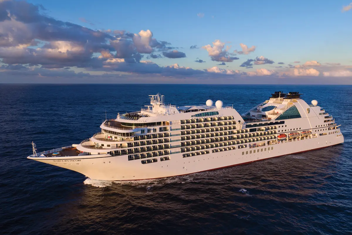 Die Seabourn Encore fährt im goldenen Abendlicht auf dem tiefblauen Meer unter leicht bewölktem Himmel.