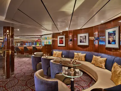 Die stilvolle Bar-Lounge 'The Club' an Bord der Seabourn Encore zeigt geschwungene blaue Sofas und edle Holzvertäfelung.