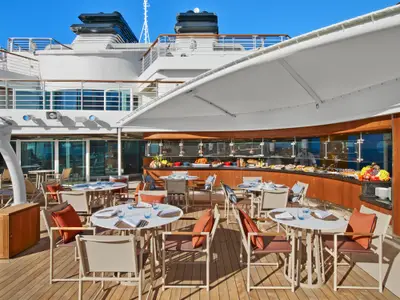 Außenbereich des Buffet-Restaurants an Bord der Seabourn Encore mit gedeckten Tischen und Sonnensegel.