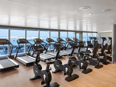 Das helle Fitness-Studio an Bord der Seabourn Encore ist mit modernen Laufbändern und Cardio-Geräten vor großen Panoramafenstern ausgestattet.