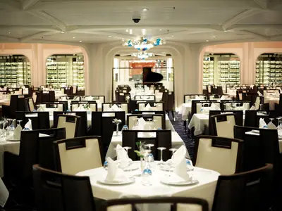 Blick in das elegant gestaltete, festlich eingedeckte Restaurant an Bord der Seabourn Encore mit symmetrisch angeordneten Tischen.