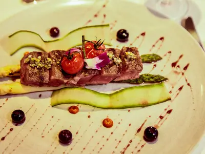 Ein kunstvoll angerichtetes Fleischgericht mit Spargel und Tomaten an Bord der Seabourn Encore.