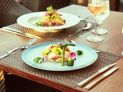 Ein kunstvoll angerichtetes Hummergericht mit Spargel und essbaren Blüten an Bord der Seabourn Encore im Restaurant The Colonnade.