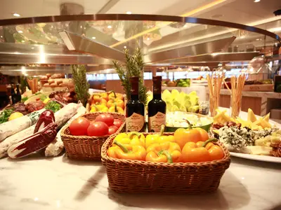 Ein reichhaltiges Buffet mit frischem Gemüse, Tomaten, Paprika, Käse und Essigflaschen an Bord der Seabourn Encore.