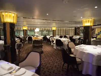 Das luxuriöse Restaurant an Bord der Seabourn Encore besticht durch weiß gedeckte Tische und warme Säulenbeleuchtung.