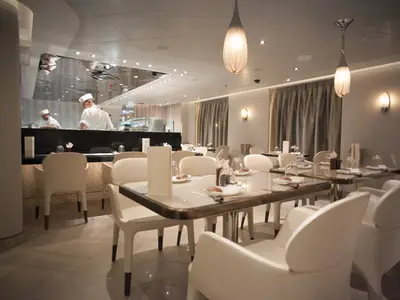 Elegant eingedeckte Tische und zwei Köche an einer Sushi-Theke im Restaurant an Bord der Seabourn Encore.