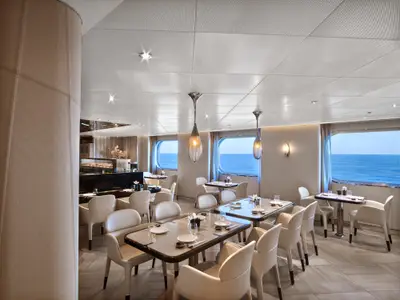 Elegantes Sushi-Restaurant an Bord der Seabourn Encore mit gedeckten Tischen, stilvollen Hängelampen und Meerblick durch große Fenster.