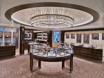 Ein stilvoller Juwelierladen an Bord der Seabourn Encore mit gläsernen Vitrinen, hellem Teppich und einem großen Kristallkronleuchter.