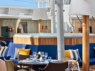 Ein stilvoller Loungebereich mit gedecktem Tisch und hölzernem Whirlpool an Bord der Seabourn Encore.