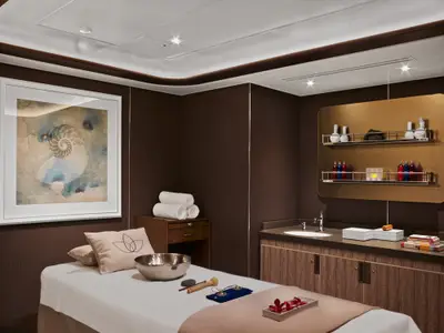 Ein Behandlungsraum im Wellness-Bereich an Bord der Seabourn Encore mit Massageliege, Klangschale und Waschbecken.