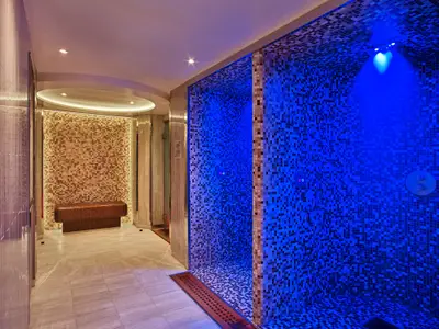 Spa-Bereich an Bord der Seabourn Encore mit blau beleuchteten Erlebnisduschen und einer beheizten Mosaikbank.