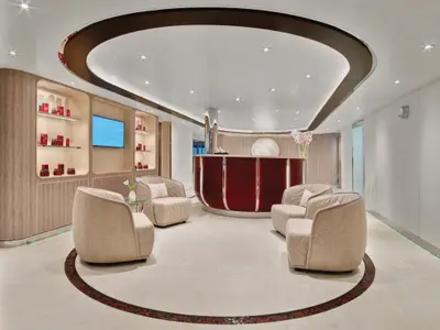 Der stilvolle Empfangsbereich des Wellnessbereichs an Bord der Seabourn Encore mit gemütlichen Sesseln und einer runden Rezeption.