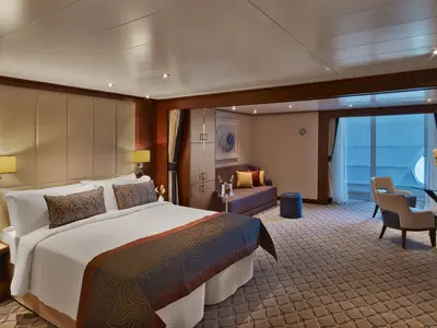 Eine großzügige, elegant eingerichtete Suite an Bord der Seabourn Encore mit Doppelbett, Couch und Balkonzugang.