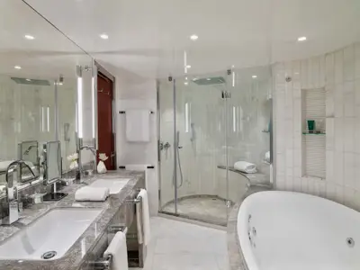 Das elegante Marmor-Badezimmer einer Suite an Bord der Seabourn Encore mit Doppelwaschbecken, Glasdusche und Badewanne.