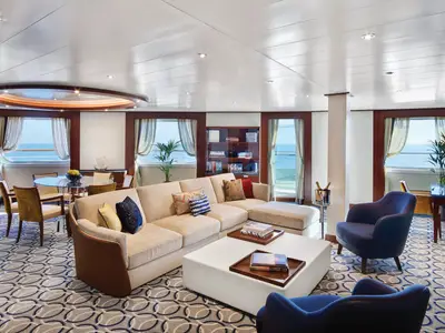 Elegant eingerichteter Wohn- und Essbereich in einer Suite an Bord der Seabourn Encore mit großem Sofa, Sesseln und Meerblick.