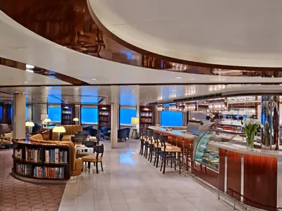 Die gemütlich eingerichtete Bar und Lounge an Bord der Seabourn Ovation bietet Sessel, Bücherregale und Ausblick auf das tiefblaue Meer.