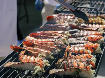 Nahaufnahme von zahlreichen Hummerschwänzen, die frisch auf dem Grill an Bord der Seabourn Ovation zubereitet werden.