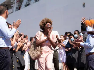 Eine freudige Passagierin läuft durch ein Spalier der klatschenden Crew an Bord der Seabourn Ovation.