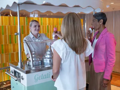 Eine Mitarbeiterin serviert Gästen an Bord der Seabourn Ovation Eiswaffeln an einer Gelato-Station.