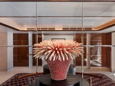 Eine rot-weiße moderne Kunstskulptur in einem eleganten Flur mit Holzpaneelen und Spiegeln an Bord der Seabourn Ovation.