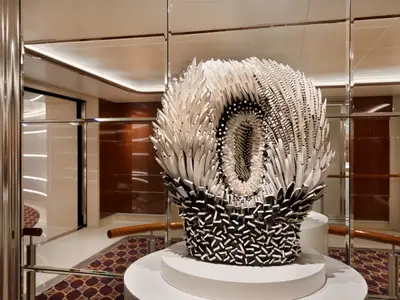 Eine detailreiche schwarz-weiße Skulptur an Bord der Seabourn Ovation, umgeben von Spiegeln und Holzvertäfelungen.