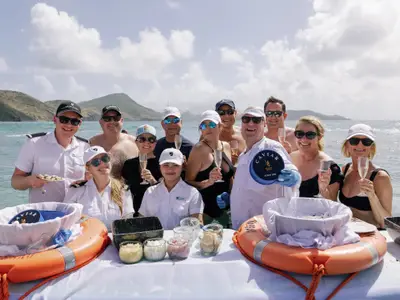 Crew und Passagiere stehen lächelnd im türkisblauen Meer während des 'Caviar in the Surf'-Events an Bord der Seabourn Ovation.