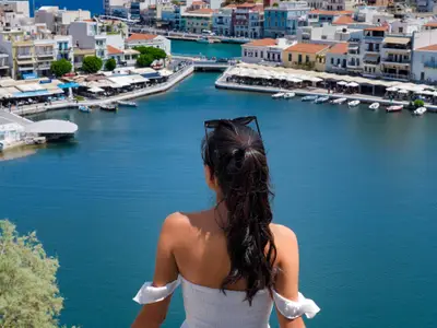 Eine Frau blickt bei einem Landausflug der Seabourn Ovation von oben herab auf eine malerische griechische Bucht mit Booten.