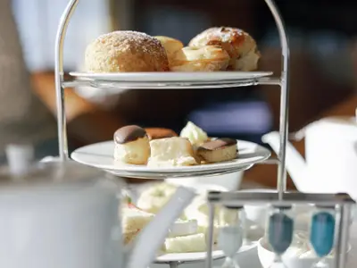 Nahaufnahme einer dreistöckigen Etagere mit Gebäck, Scones und feinen Desserts beim Afternoon Tea an Bord der Seabourn Ovation.