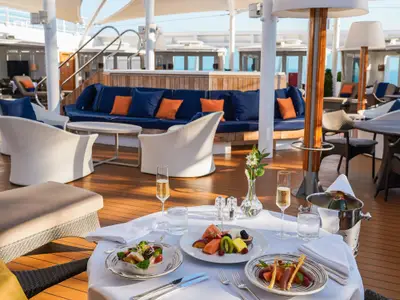 Ein gedeckter Tisch mit Champagner und frischem Obst im luxuriösen Bereich 'The Retreat' an Bord der Seabourn Ovation.