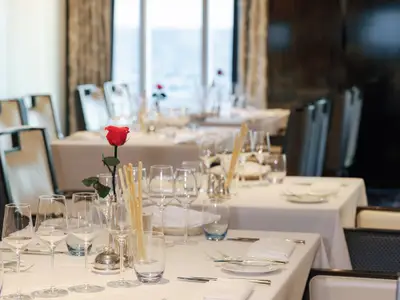 Gedeckter Tisch im eleganten Restaurant an Bord der Seabourn Ovation mit Weingläsern, Grissini und einer roten Rose.