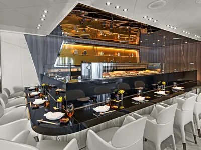 Elegant gestaltetes Sushi-Restaurant an Bord der Seabourn Ovation mit einem dunklen Tresen, weißen Ledersesseln und glänzender Deckenverkleidung.
