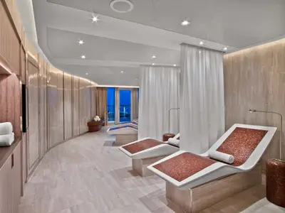 Blick in den eleganten Spa-Bereich an Bord der Seabourn Ovation mit beheizten Mosaik-Entspannungsliegen und weißen Vorhängen.