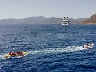 Passagiere der Seabourn Ovation fahren Bananenboot auf dem blauen Meer mit dem Luxusschiff im Hintergrund.
