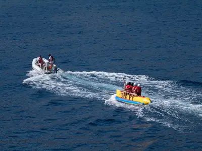 Passagiere der Seabourn Ovation vergnügen sich beim Bananenbootfahren auf dem blauen Meer, gezogen von einem Beiboot.