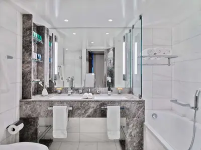 Das luxuriöse Marmorbadezimmer in einer Suite an Bord der Seabourn Ovation mit Doppelwaschbecken, großem Spiegel und Badewanne.