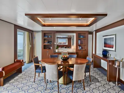 Blick in den großzügigen Essbereich einer luxuriösen Suite an Bord der Seabourn Ovation mit rundem Tisch und Holzmöbeln.
