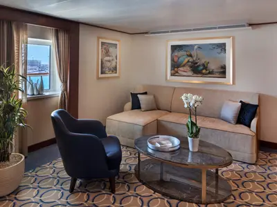 Der gemütliche Wohnbereich einer luxuriösen Suite an Bord der Seabourn Ovation mit Sofa, Sessel und Blick aufs Meer.
