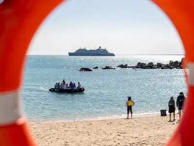 Blick durch einen Rettungsring auf ein Zodiac voller Gäste vor dem Expeditionsschiff Seabourn Pursuit vor der Küste.