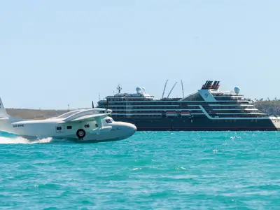 Ein historisches Wasserflugzeug auf dem türkisfarbenen Meer vor dem luxuriösen Expeditionsschiff Seabourn Pursuit.