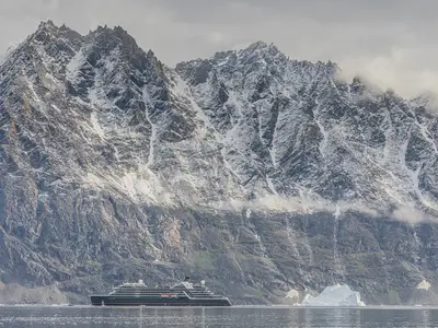 Das Expeditionsschiff Seabourn Pursuit vor einer gewaltigen, dramatischen Kulisse aus schneebedeckten Bergen.